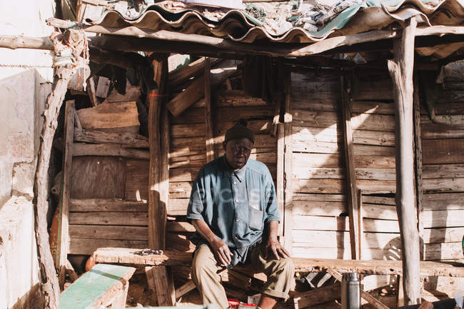 Yoff, Senegal- Dezembro 6, 2017: Retrato de homem sentado e descansando no banco em casa na aldeia — Fotografia de Stock