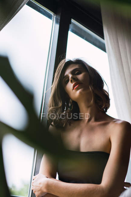 Низький кут зору вродливу брюнетку жінка позує біля вікна — Stock Photo