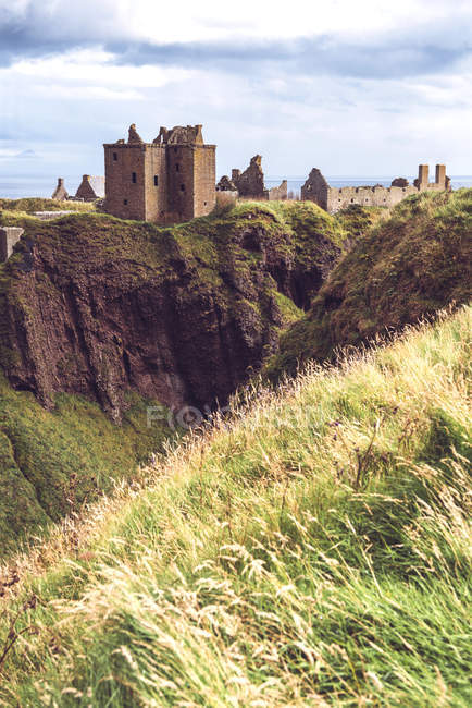 Vista lejana del castillo de Dunnottar parado en el acantilado en el telón de fondo del mar . - foto de stock