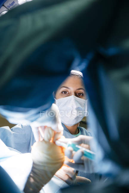 Retrato del asistente femenino mirando la operación quirúrgica - foto de stock