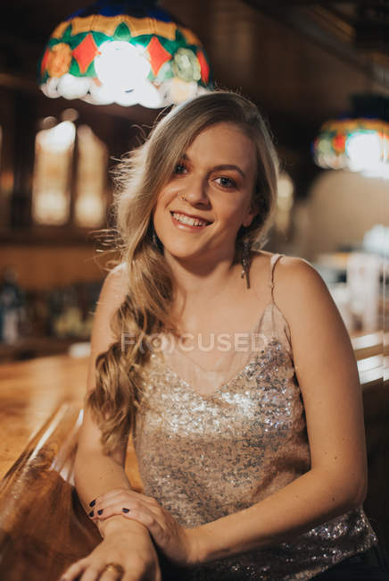 Elegante rubia posando en el mostrador del bar y mirando a la cámara - foto de stock