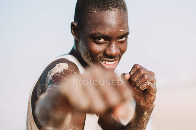 Yoff, senegal- 6. Dezember 2017: Porträt eines fröhlichen Afrikaners, der mit ausgestreckter Faust vor der Kamera posiert. — Stockfoto