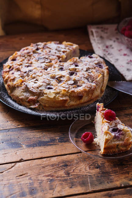 Christmas cake with one sliced piece on wooden table — Stock Photo
