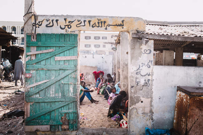 Goree, Senegal- 6 dicembre 2017: Gruppo di persone africane sedute in un rifugio semidistrutto in strada nella città povera . — Foto stock