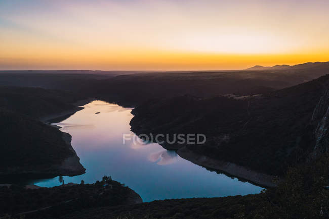 Живописный панорамный пейзаж спокойной реки, отражающий красочное небо заката — стоковое фото