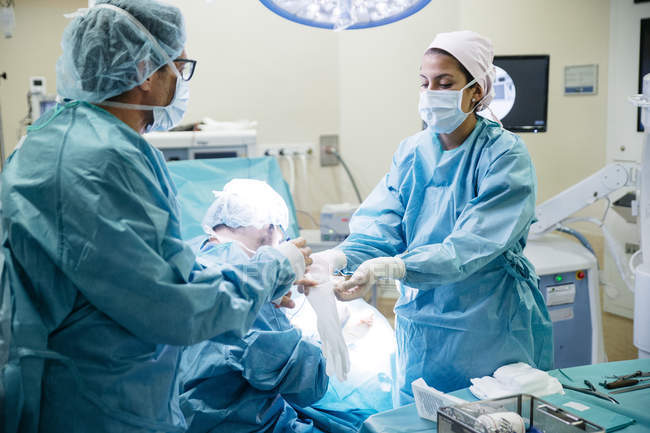 Pessoal médico que veste luvas antes da operação na sala de cirurgia — Fotografia de Stock