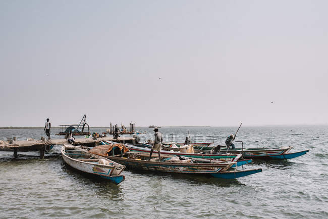Goree, Senegal - 6 de diciembre de 2017: Gente en barcos flotando en la orilla del río - foto de stock