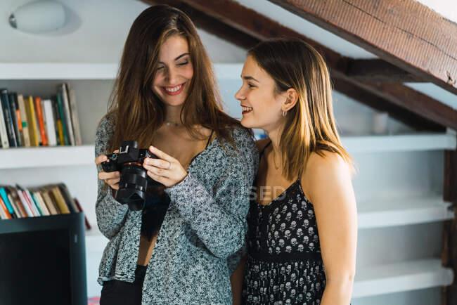 Cheerful woman with camera having fun with young girlfriend at home. — Stock Photo