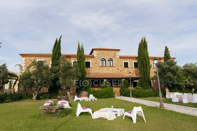 Exterior of mansion with cypress trees and lawn with catering and lounge zone — Stock Photo