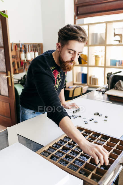 Retrato del hombre que trabaja en la fabricación de libros y componer letras de prensa de impresión en el escritorio . - foto de stock