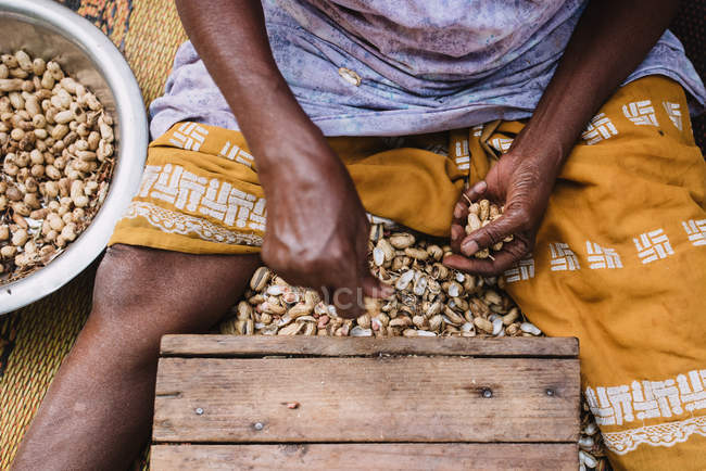 Crop shot from above of male midsection shelling roasted nuts. — Stock Photo