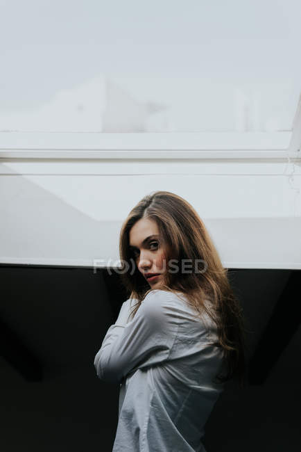 Vista laterale della giovane ragazza bruna che guarda la fotocamera — Foto stock