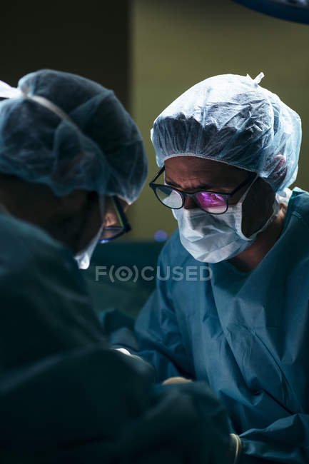 Retrato de cirujanos concentrados explorando al paciente en el hospital - foto de stock