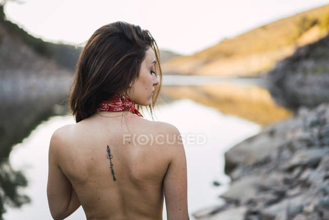 Rear view of topless brunette girl looking over shoulder at back — Stock Photo