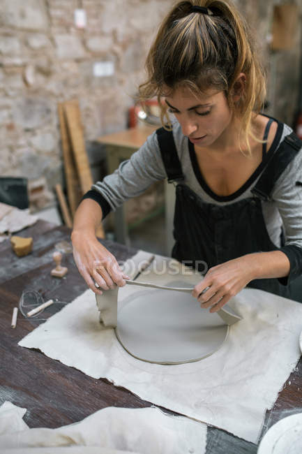 Blonde woman carefully working with clay on desktop — Stock Photo