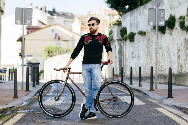 Stylish man posing with bicycle on street scene — Stock Photo