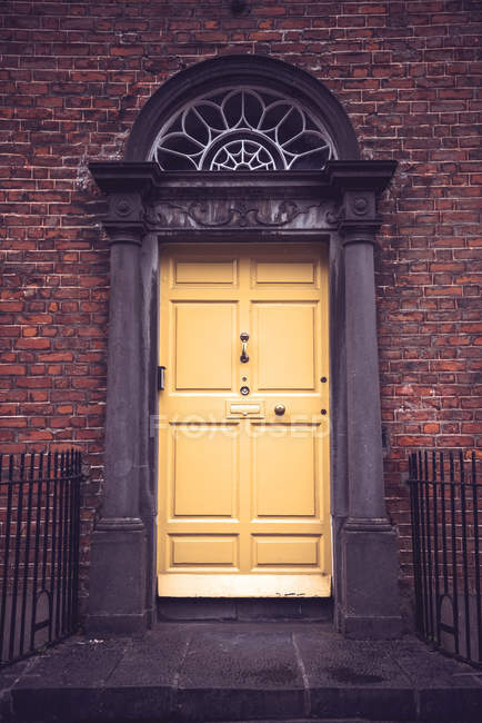 Façade extérieure avec porte jaune en mur de briques — Photo de stock