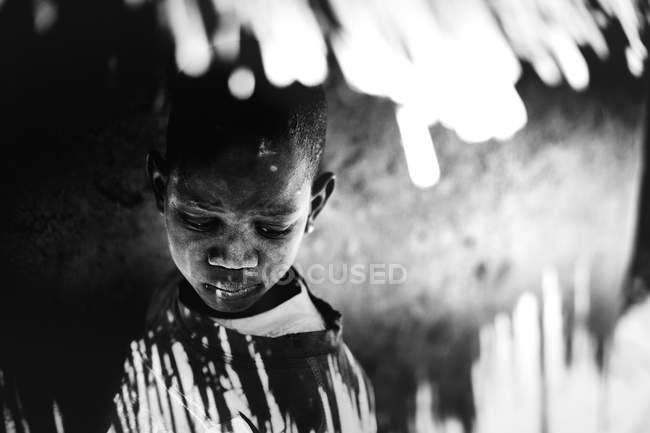 Goree, senegal- 6. Dezember 2017: Porträt eines Jungen im Schatten des Strohdachs, der nachdenklich nach unten schaut — Stockfoto