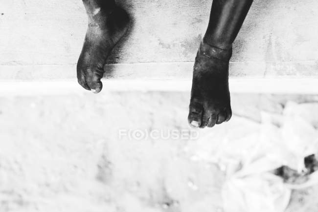 Crop shot of barefoot child sitting on concrete. — Stock Photo