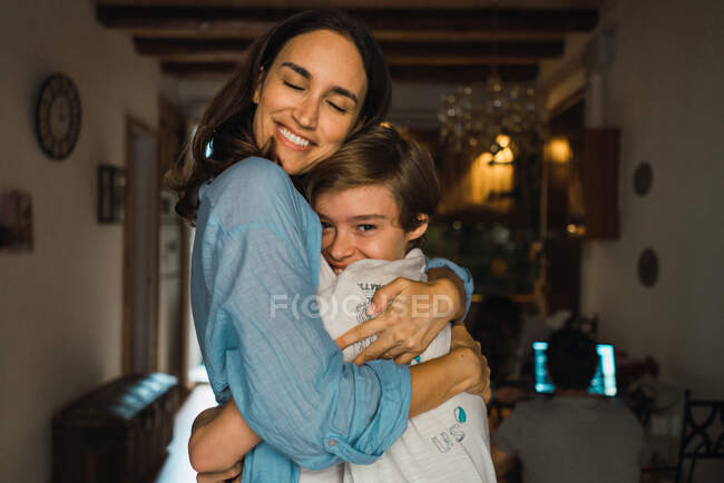 Alegre madre abrazando a su hijo - foto de stock