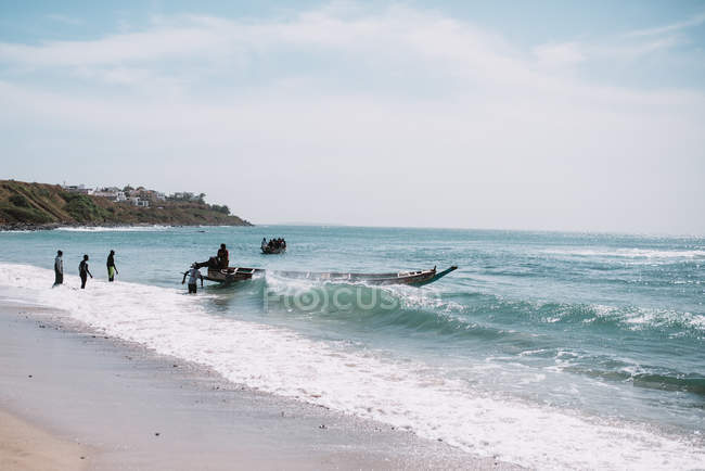 Goree, Senegal- Dezembro 6, 2017: Barco flutuando perto da costa em mar ondulado no dia ensolarado . — Fotografia de Stock