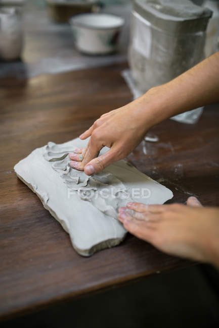 Обрізати зображення жіночих рук, замішуючи глиняний шматок на столі — стокове фото