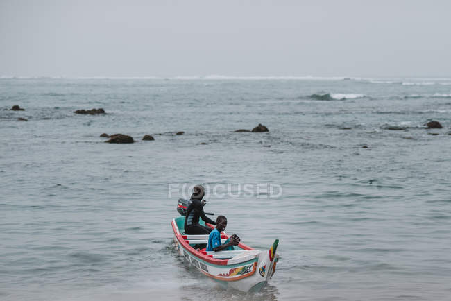 Goree, senegal- 6. Dezember 2017: zwei Männer beim Bootfahren im wogenden Meer an einem trüben Tag. — Stockfoto