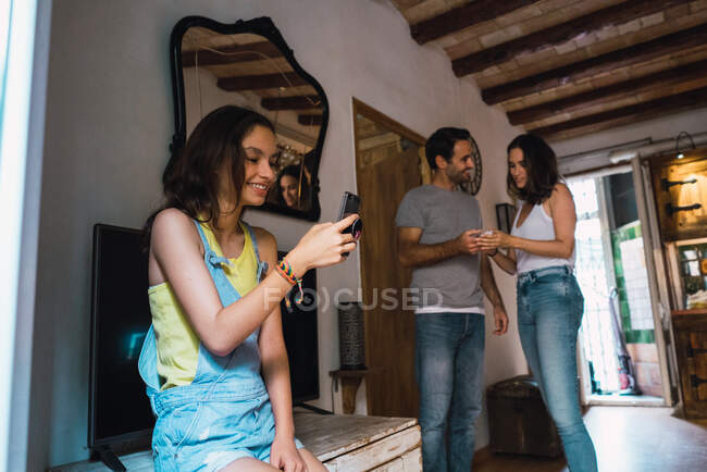 Menina com telefone em casa com os pais — Fotografia de Stock