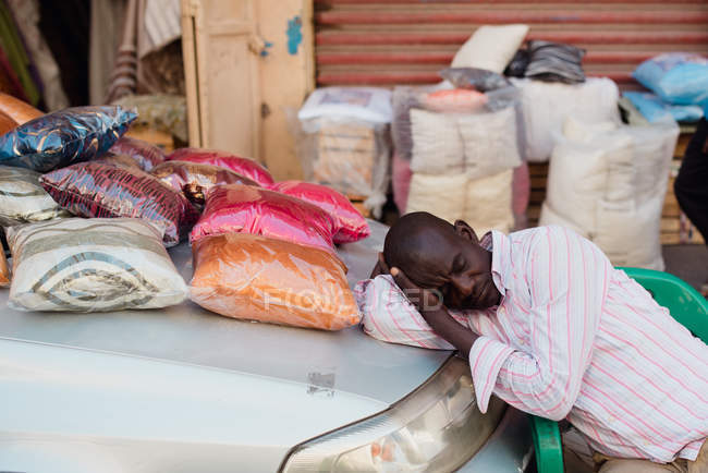 Goree, Senegal - 6 de diciembre de 2017: Hombre durmiendo en el maletero del automóvil mientras negociaba en el mercado en una pequeña ciudad africana . - foto de stock