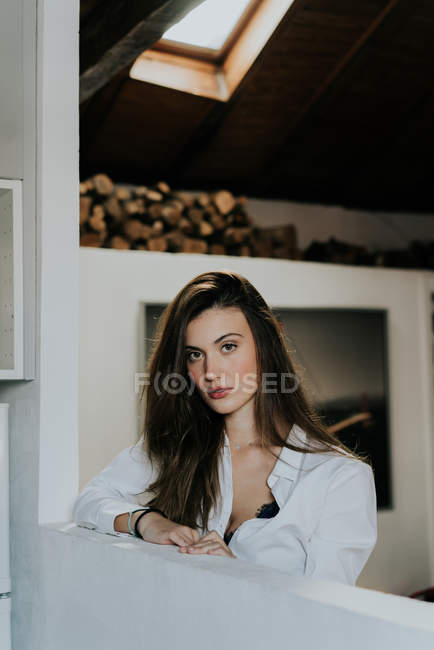 Charmantes brünettes Mädchen in weißem Hemd posiert zu Hause und schaut in die Kamera — Stockfoto