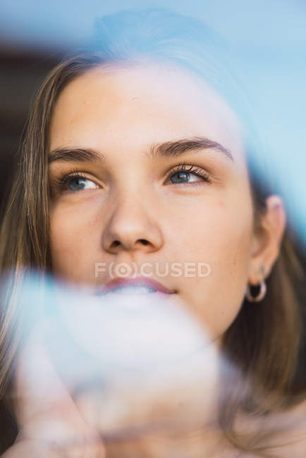 Vue à travers le verre à la jeune femme regardant loin — Photo de stock