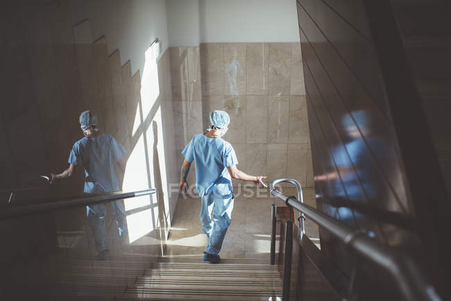 Вид ззаду чоловіка в лікарській формі спускається по сходах в лікарні — стокове фото