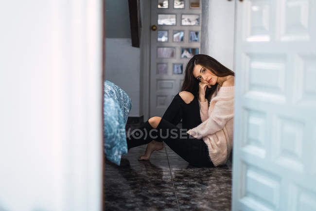 Menina pensativo sentado no corredor e olhando para a câmera — Fotografia de Stock