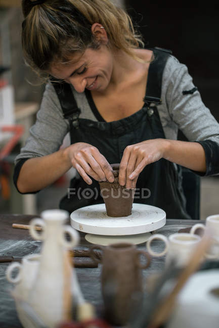 Smiling woman modeling pot from pot — Stock Photo