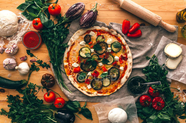 Top view of composed vegetables with cooked pizza and ingredients on wood. — Stock Photo