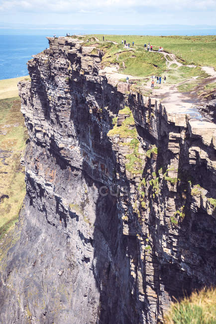 People walking on massive cliffs of Moher on Atlantic ocean coast — Stock Photo