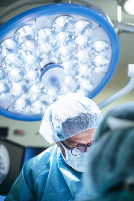 Retrato del médico con máscara en la sala de cirugía durante la operación - foto de stock