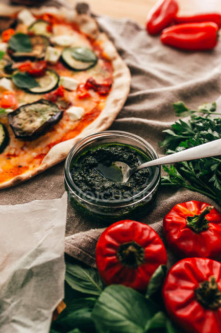 Close up view of jar with green organic sauce served for delicious vegetable pizza. — Stock Photo