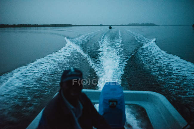 Portrait of man sitting in motorboat and driving it in evening dusk, Yoff, Senegal — Stock Photo