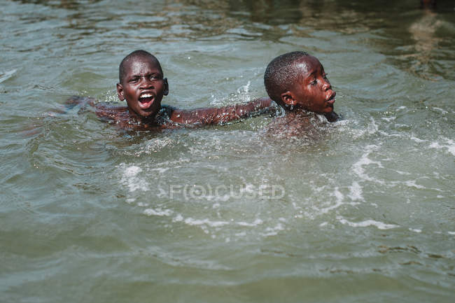 Goree, Senegal - 6 de diciembre de 2017: Niños alegres nadando juntos en el agua . - foto de stock