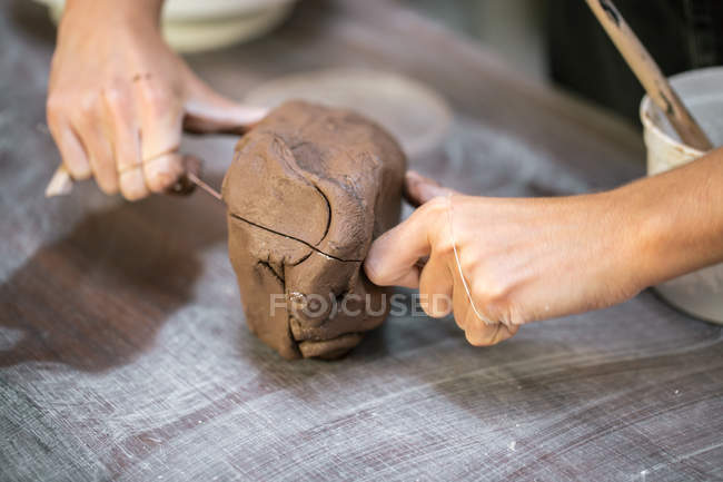 Crop female hands slicing piece of clay with string — Stock Photo