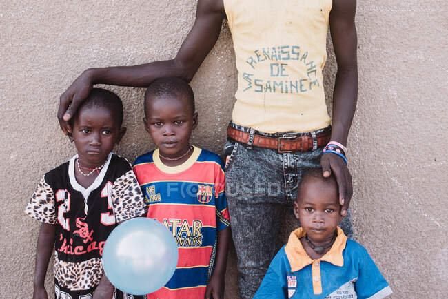 Crop man avec des garçons africains posant contre le mur dans la rue. — Photo de stock