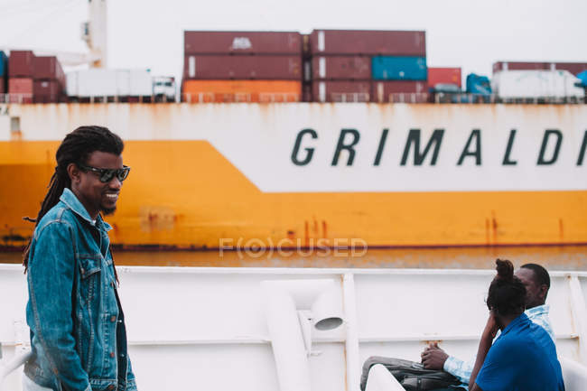 Goree, Senegal- 6 dicembre 2017: Vista laterale dell'uomo con gli occhiali da sole in piedi sulla nave cargo . — Foto stock