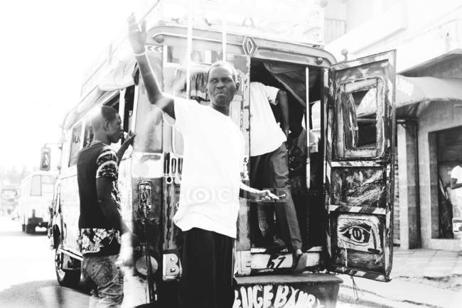 Goree, Senegal- 6 dicembre 2017: Uomo che alza la mano prima di entrare nel bagagliaio del furgone . — Foto stock