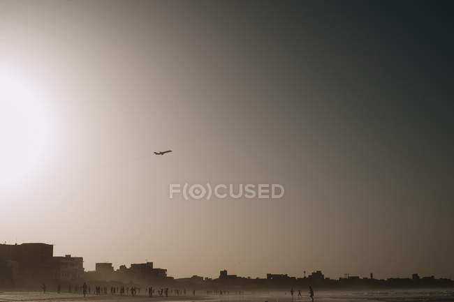 Paesaggio con aereo che vola sopra la piccola città sulla costa oceanica . — Foto stock
