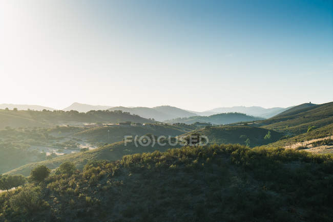 Paesaggio panoramico della nebbiosa valle delle montagne illuminata dal sole — Foto stock