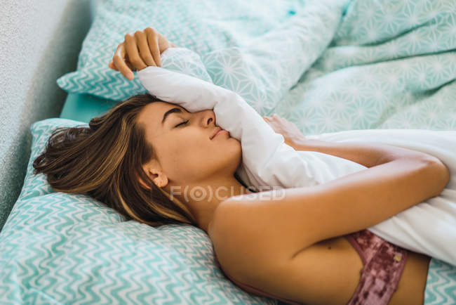 Menina dormindo na cama com lençóis azul modelado e  . — Fotografia de Stock