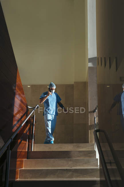 Chirurg telefoniert und geht im Treppenhaus im Krankenhausflur — Stockfoto