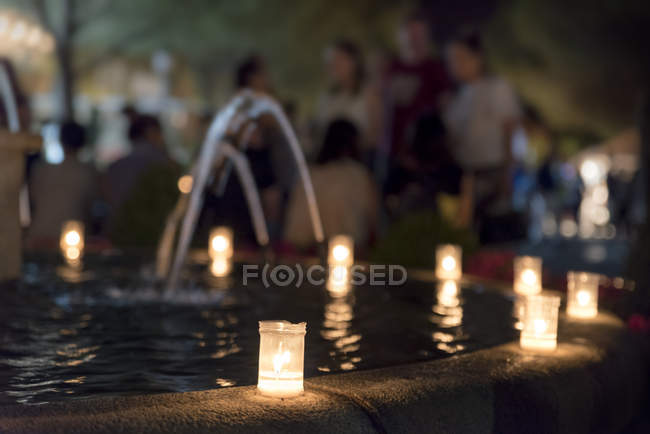 Candele accese sul bordo della fontana nella piazza del villaggio — Foto stock