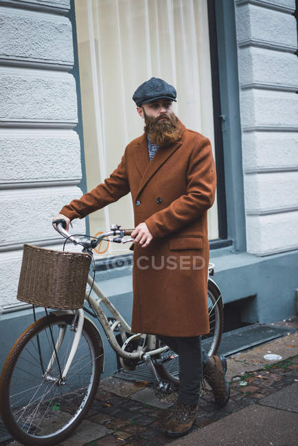 Side view of bearded man walking with vintage bicycle on city street. — Stock Photo